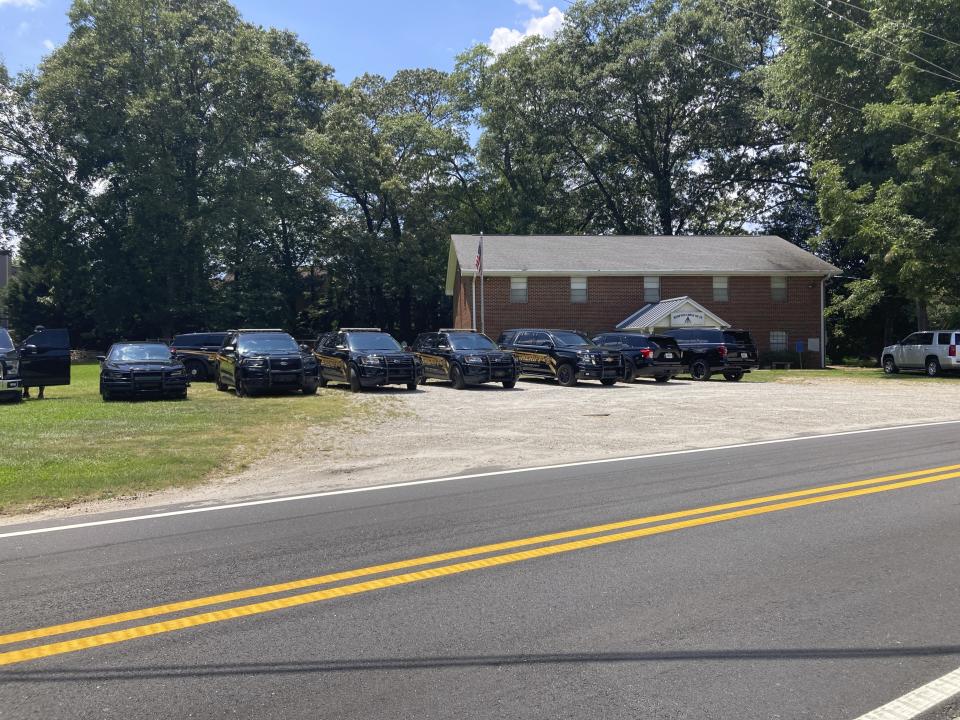 Henry County sheriff's vehicles are lined up in Hampton, Ga., on Sunday, July 16, 2023, as deputies meet to discuss the manhunt for Andre Longmore. Police say Longmore shot and killed four people in a nearby neighborhood on Saturday, July 15, 2023. (AP Photo/Jeff Amy)