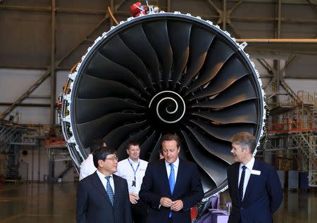 Britain's Prime Minister David Cameron (C) talks with Rolls-Royce's President of Aerospace Tony Wood (R) and Vietnam Airlines' President and CEO Pham Ngoc Minh (L) in front of a Rolls-Royce engine at a hangar in Noi Bai airport, in Hanoi, July 29, 2015. REUTERS/Stringer