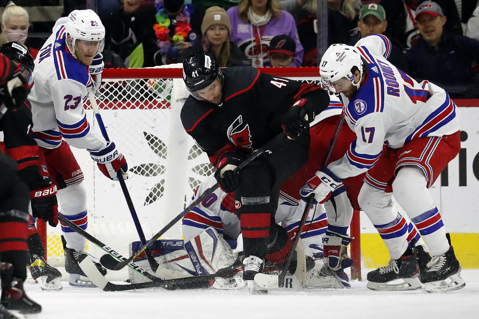 Carolina Hurricanes' Josh Leivo (41) battles for the puck between New York Rangers' Adam Fox (23) and Kevin Rooney (17) in front of Rangers goaltender Alexandar Georgiev during the first period of an NHL hockey game in Raleigh, N.C., Friday, Jan. 21, 2022. (AP Photo/Karl B DeBlaker)