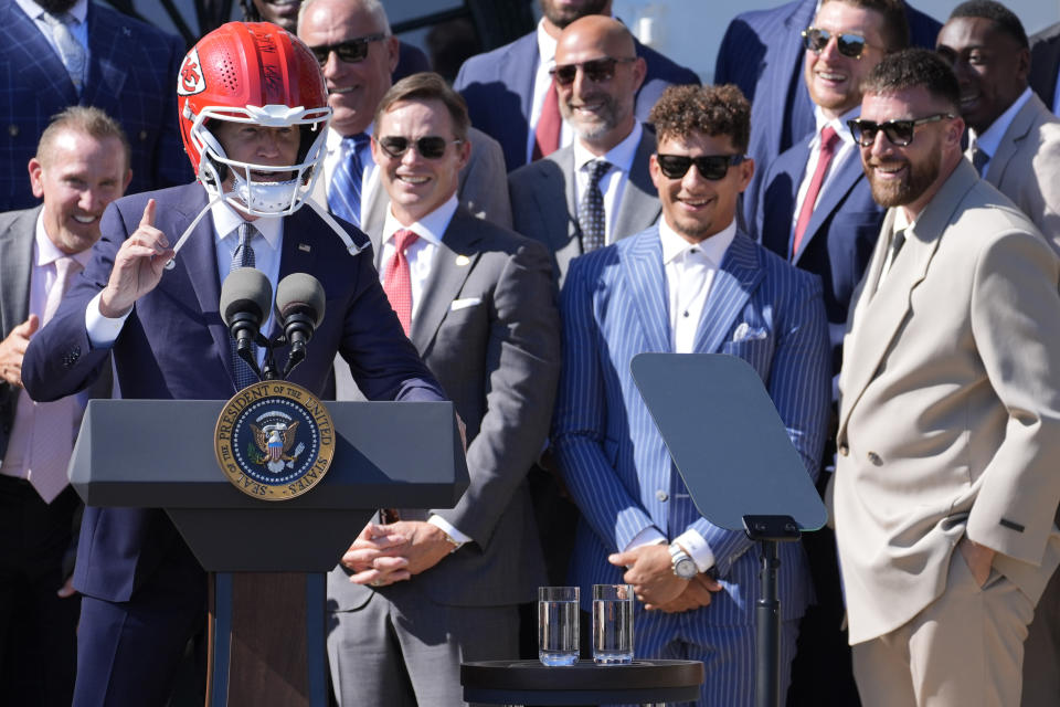 El quarterback de los Chiefs de Kansas City, Patrick Mahomes (segundo desde la derecha), y el tight end de los Chiefs de Kansas City, Travis Kelce (derecha), observan mientras el Presidente, Joe Biden lleva puesto el casco de los Chiefs mientras se expresa durante un evento en el Jardín Sur con los campeones del Super Bowl, Kansas Ciy Chiefs, el viernes 31 de mayo de 2024, para celebrar su temporada de campeones con el triunfo en el Super Bowl LVIII. (AP Foto/Evan Vucci)