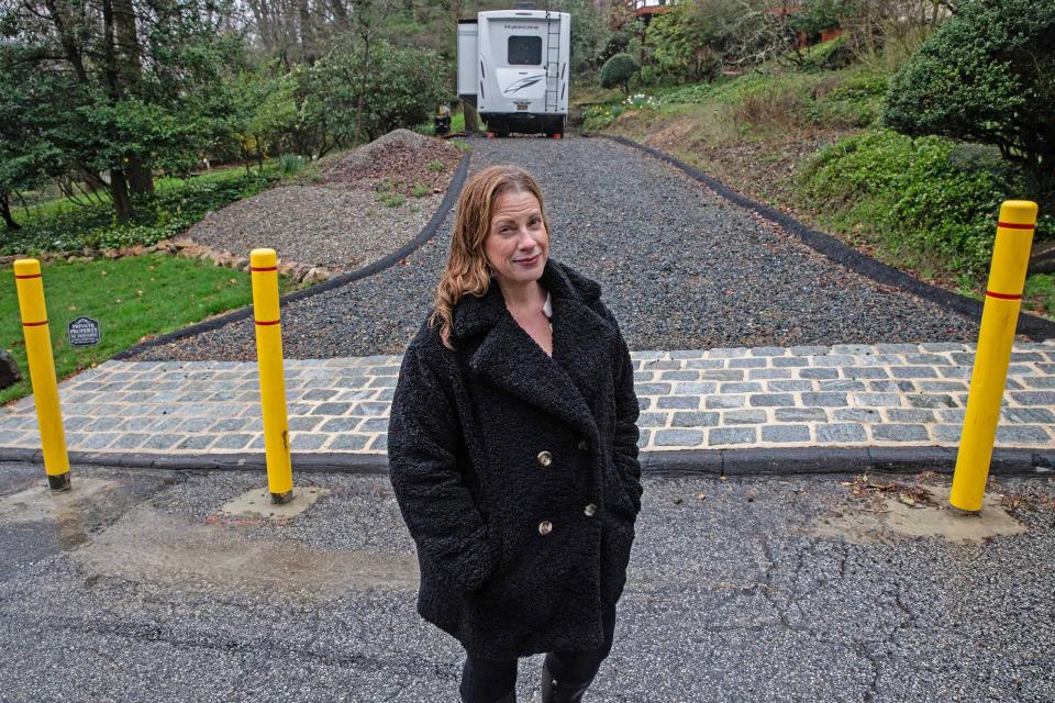 Homeowner and resident Amanda Clappsy stands in front of the bollards recently installed to block her driveway and RV at the Westminster community in Wilmington, Tuesday, April 2, 2024. Clappsy, after clearing with the community’s prior board, reconfigured her driveway so she could park her RV but has been having problems with the new civic association board due to her RV.