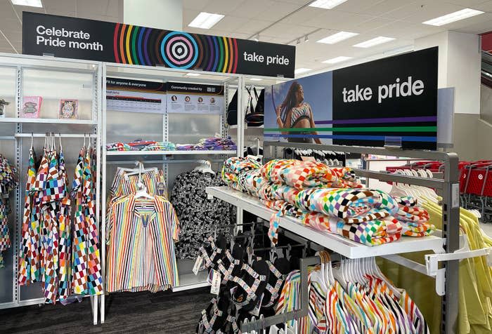 Store display promoting Pride Month features colorful, patterned clothing and accessories with "Celebrate Pride month" and "take pride" signage