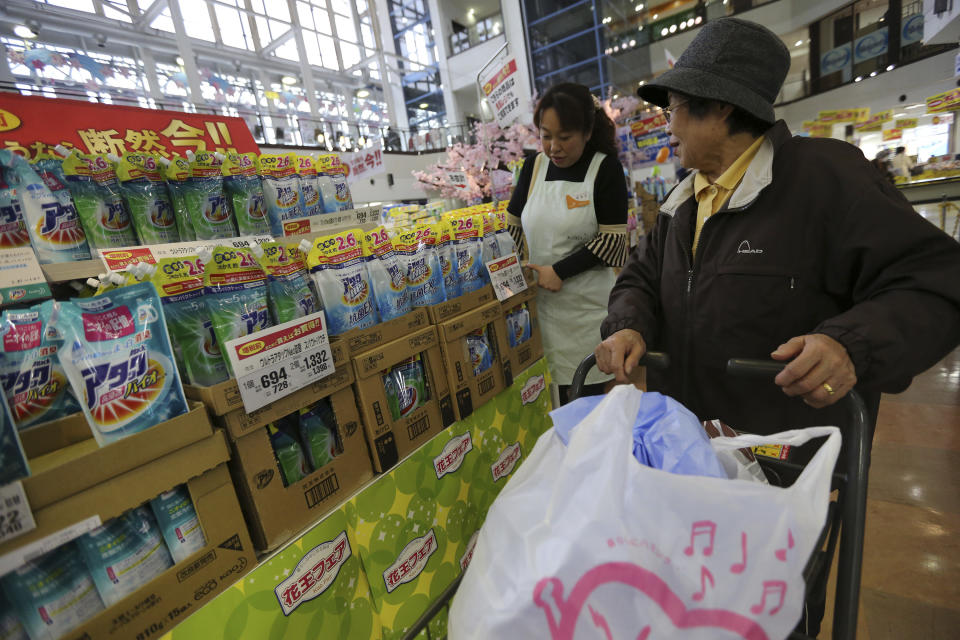 In this Thursday, March 27, 2014 photo, a customer, right, chats with a shop clerk at a bargain sale at a supermarket in Shinurayasu, near Tokyo. Japanese household spending fell 1.5 percent in February from a year earlier, suggesting consumers are tightening belts ahead of an April 1 hike in the country's sales tax. The government also reported Friday, March 28 that core consumer prices rose 1.3 percent in February, though a large share of the increase was due to rising energy costs. (AP Photo/Eugene Hoshiko)