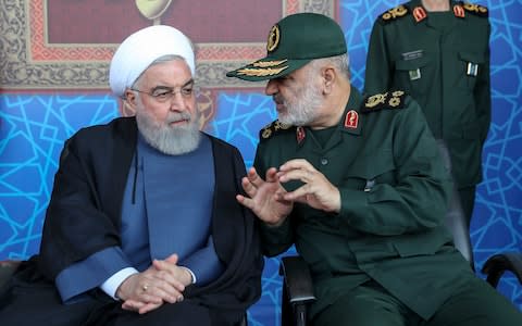 President Hassan Rouhani, left, listens to chief of the Revolutionary Guard Gen. Hossein Salami at a military parade marking 39th anniversary of outset of Iran-Iraq war - Credit: Office of Iranian Presidency