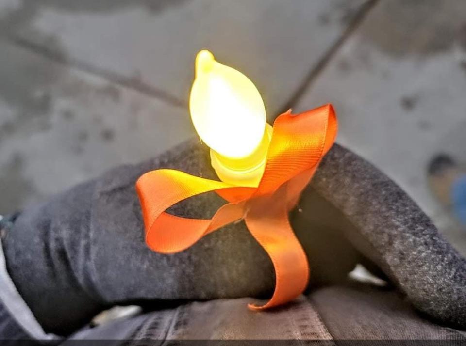 Linda Varela Adams holds a light and an orange ribbon during a candlelight vigil for her son in Colorado on Nov. 19, 2023.