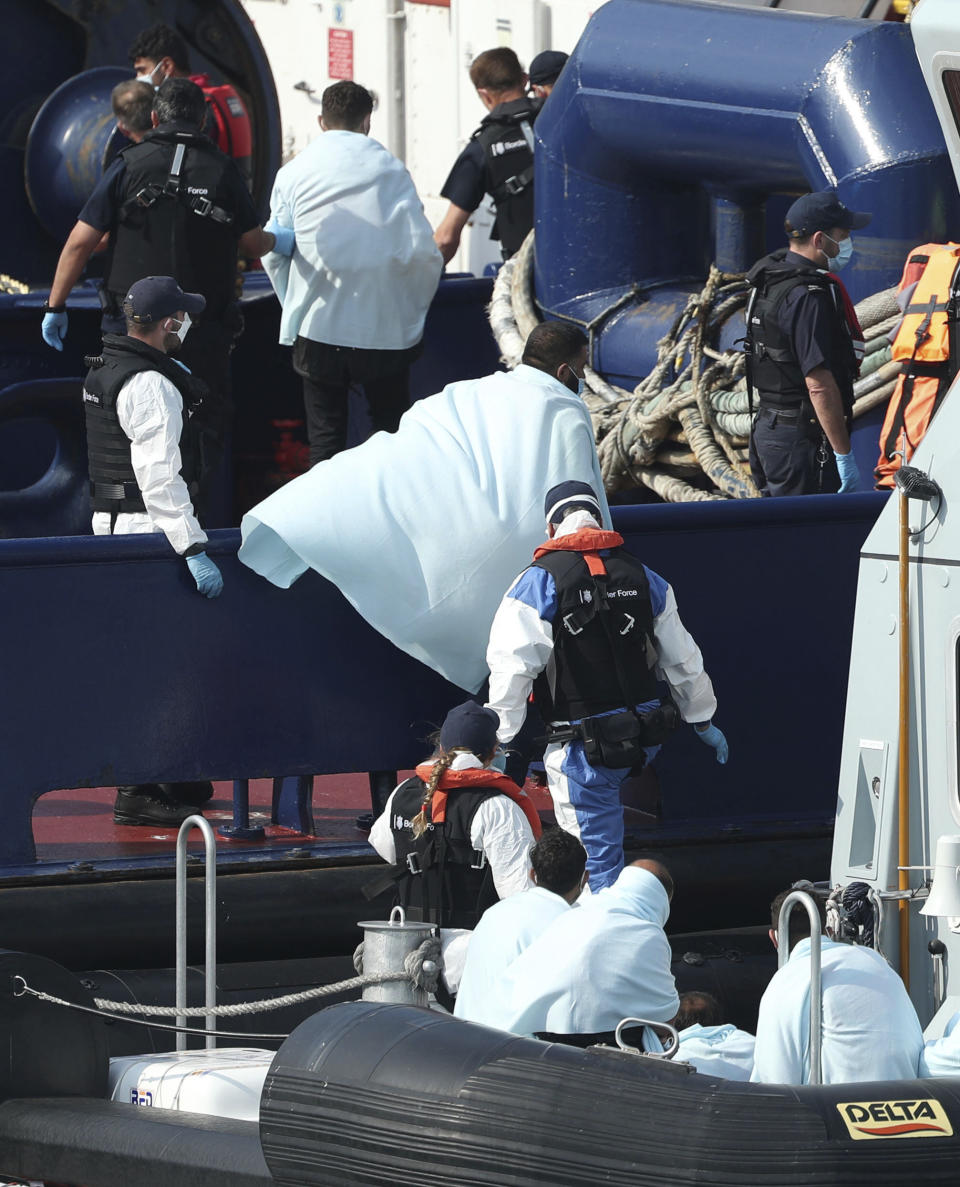 A Border Force vessel brings a group of people thought to be migrants into the port city of Dover, southern England, Sunday Aug. 9, 2020. Many migrants have used small craft during the recent hot calm weather to make the dangerous journey from northern France, to cross the busy shipping lanes of The Channel to reach Britain. (Yui Mok/PA via AP)