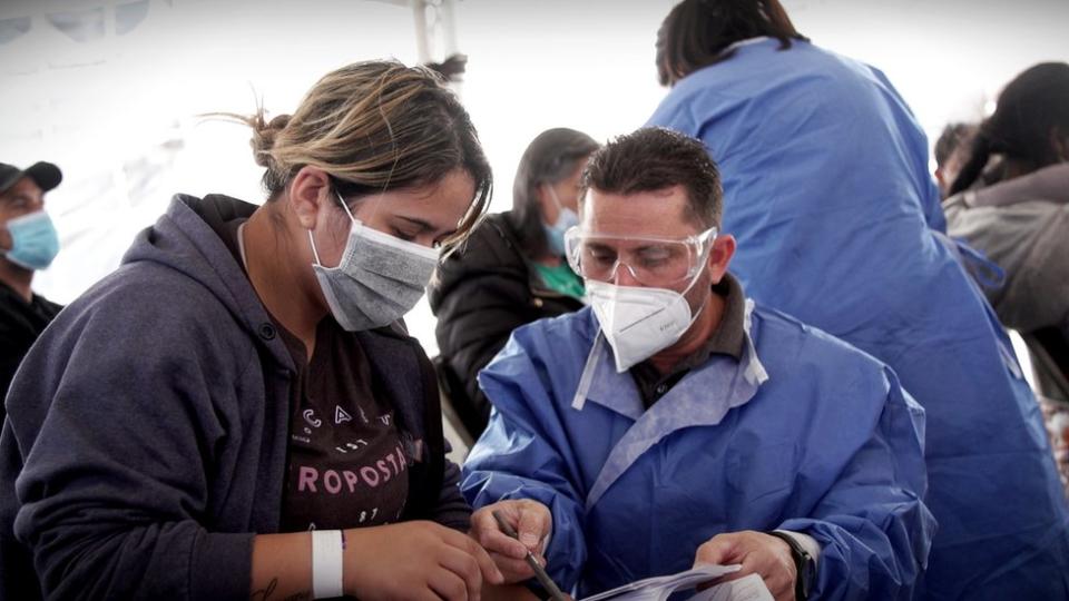 Fernando Quiroz ayudando a una migrante a llenar un formulario.