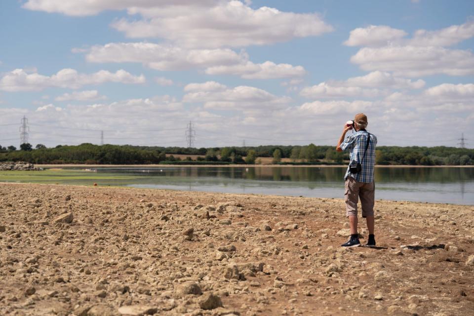 A man stands in the basin of Grafham Water near Huntingdon in Cambridgeshire, where water is receding during prolonged dry weather. (PA)