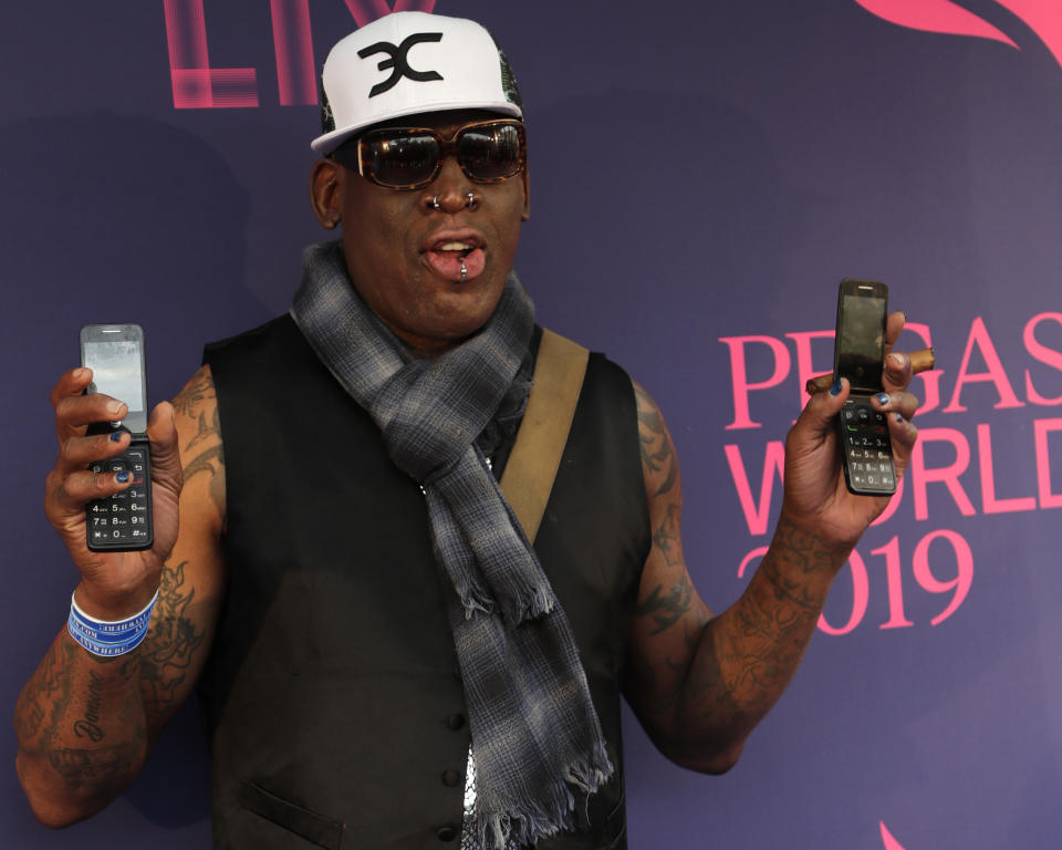 FILE - In this Jan. 26, 2019, file photo, Dennis Rodman poses with two flip phones on the blue carpet at the Pegasus World Cup Invitational Horse Race at Gulfstream Park in Hallandale Beach, Fla. The owner of a Southern California yoga studio is accusing Dennis Rodman of helping three people steal more than $3,500 in merchandise from his business. Ali Shah says security cameras captured the former NBA star walking into Vibes Hot Yoga in Newport Beach on Tuesday, May 7, 2019, with his alleged accomplices. (AP Photo/Lynne Sladky, File)