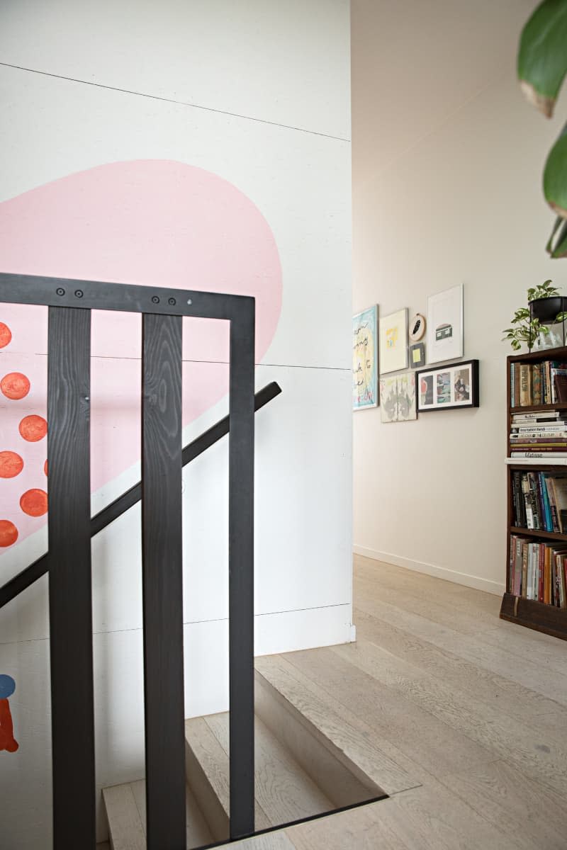 black stair railing with pink and red shape mural on the wall