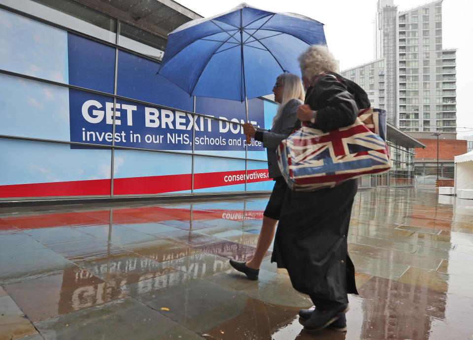 Delegates arrive in heavy rain at the Conservative Party Conference in Manchester, England, Tuesday, Oct. 1, 2019. Britain's Prime Minister Boris Johnson said Tuesday that his government prepared at last to make firm proposals for a new divorce deal with the European Union. Britain is due to leave the 28-nation bloc at the end of this month, and EU leaders are growing impatient with the U.K.'s failure to set out detailed plans for maintaining an open border between Northern Ireland and Ireland — the key sticking point to a deal. (AP Photo/Frank Augstein)