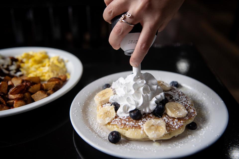 Tania Trejo adds whipped cream to a banana, blueberry and lechera pancake at Abuela’s Little Kitchen January 21, 2023.