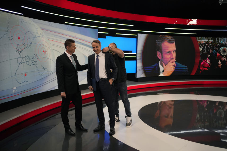 Greece's Prime Minister and New Democracy leader Kyriakos Mitsotakis, center, speaks with the journalist Antonis Sroiter after an interview at Alpha television station, during his election campaign in northern Athens, Greece, Tuesday, April 25, 2023. (AP Photo/Thanassis Stavrakis)