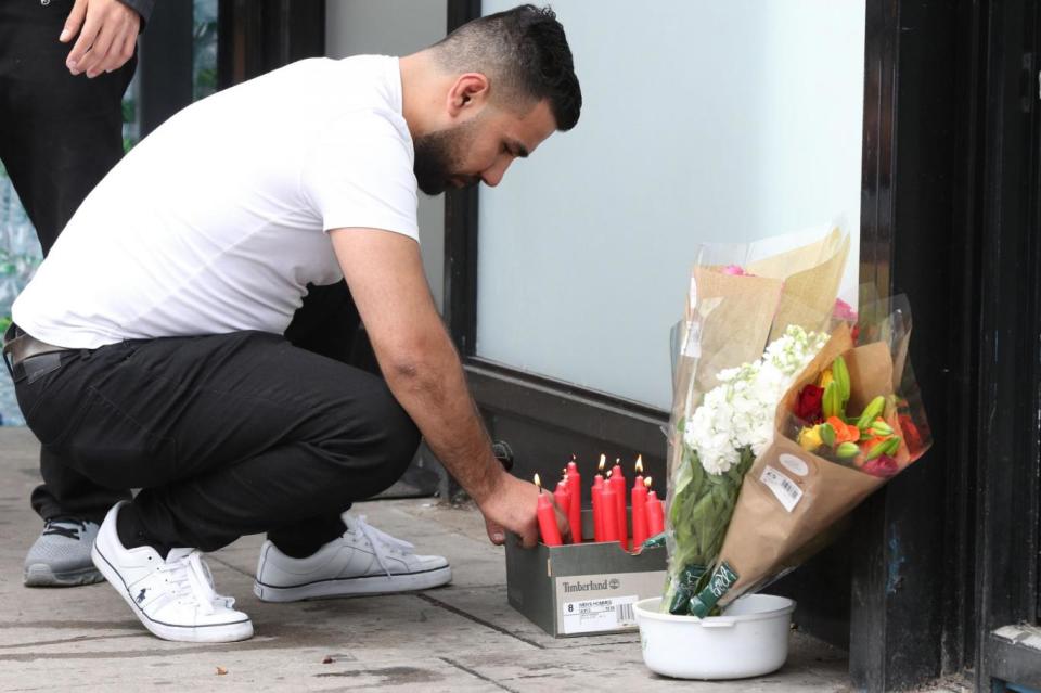 Tributes: A man lights a candle at the scene of the incident (PA)