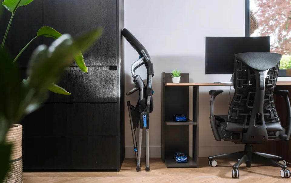 A folded chair in a niche between a closet and a computer desk.