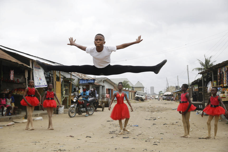 Ballet student Anthony Mmesoma Madu, center, dances in the street as fellow dancers look on in Lagos, Nigeria on Aug. 18, 2020. Cellphone video showing the 11-year-old dancing barefoot in the rain went viral on social media. Madu’s practice dance session was so impressive that it earned him a ballet scholarship with the American Ballet Theater in the U.S. (AP Photo/Sunday Alamba)