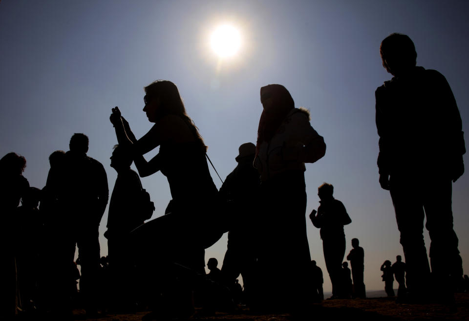 FILE - This Jan. 4, 2011 file photo shows tourists taking pictures at the site of the Giza Pyramids, Egypt during a partial solar eclipse. Solar eclipses typically attract tourists who travel around the world to remote places to witness the celestial phenomenon. Australia is expecting 50,000 visitors for a Nov. 14 solar eclipse that will be visible from the Cairns-Port Douglas area in Queensland. (AP Photo/Amr Nabil, file)