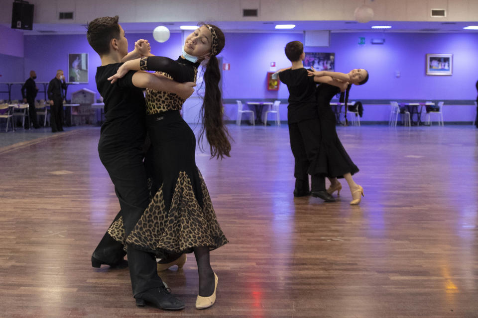 Young dancers, wearing face masks to curb the spread of COVID-19 train at the New Dancing Days School, in Rome, Wednesday, March 24, 2021. Despite the lock-down in Rome competitive dancers can still train.While much of Italy is in coronavirus lockdown, with live music and theatrical performances barred, cinemas shuttered and many sporting activities limited, competitive ballroom dancing is alive and well here, albeit with precautions. (AP Photo/Alessandra Tarantino)