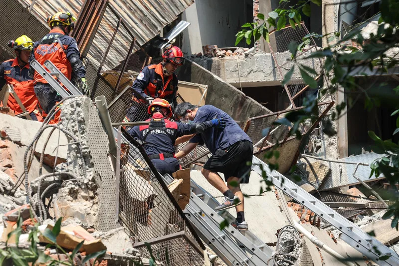 新北市中和區一處建物後棟倉庫3日上午因地震倒塌，內部受困者在消防局搜救人員馳援下順利脫困，緩步爬下樓梯。 中央社記者吳家昇攝  113年4月3日