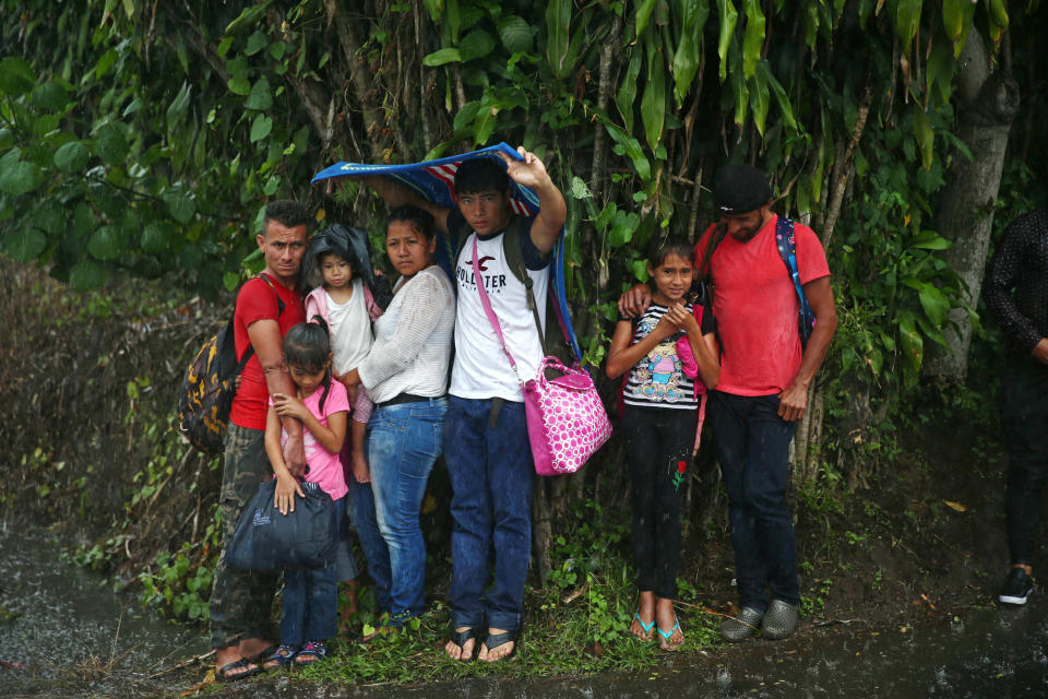 Migrant children take shelter from rain.