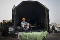 Darshan Singh, 68, sits at the back of his tractor trailer parked on a highway, adding to a convoy of farmers' trucks, trailers and tractors sretching for at least three kilometers (1.8 miles), protesting against new farm laws, at the Delhi-Haryana state border, India, Tuesday, Dec. 1, 2020. The protests started in September but drew nationwide attention last week when the farmers marched from northern Punjab and Haryana, two of India's largest agricultural states. On their way to the capital, they pushed aside concrete barricades set up by police and braved tear gas, batons and water cannons. (AP Photo/Altaf Qadri)