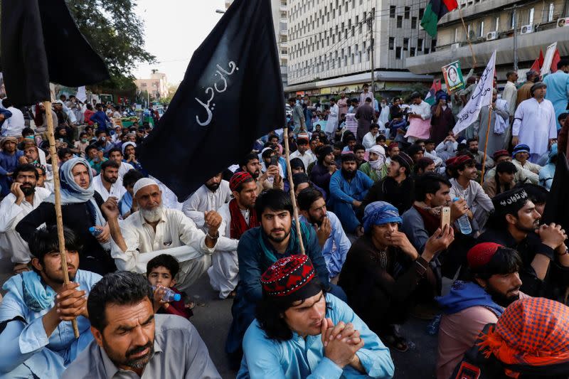 People sit with black flags as they demand an investigation following the deaths of four teenagers in Jani Khel area in Bannu District of Khyber Pakhtunkhwa (KPK) province, during a protest in Karachi,
