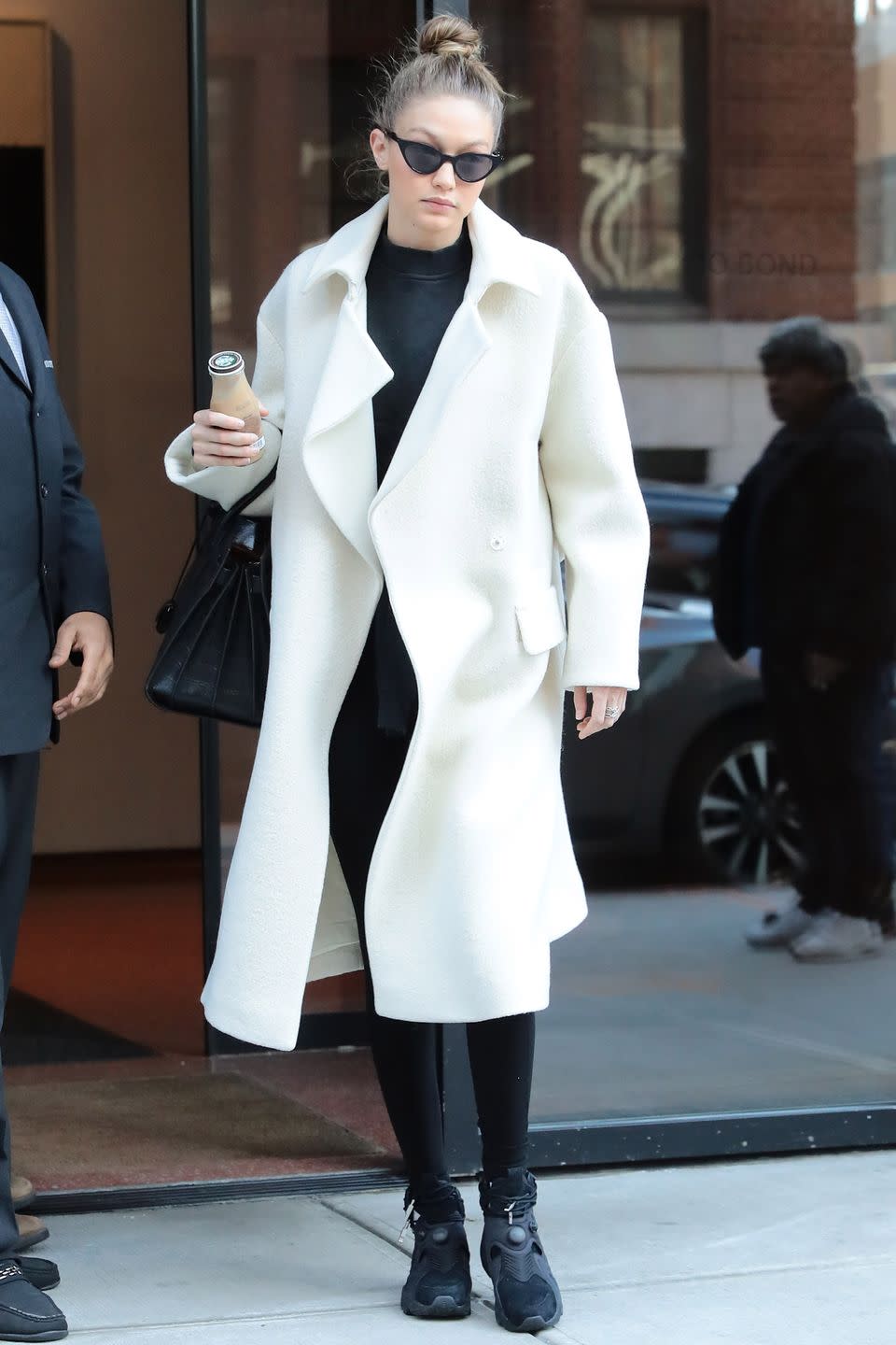 <p>In a white coat, black workout gear, black high-top sneakers, a black tote bag and black cat eye glasses while out in New York.</p>