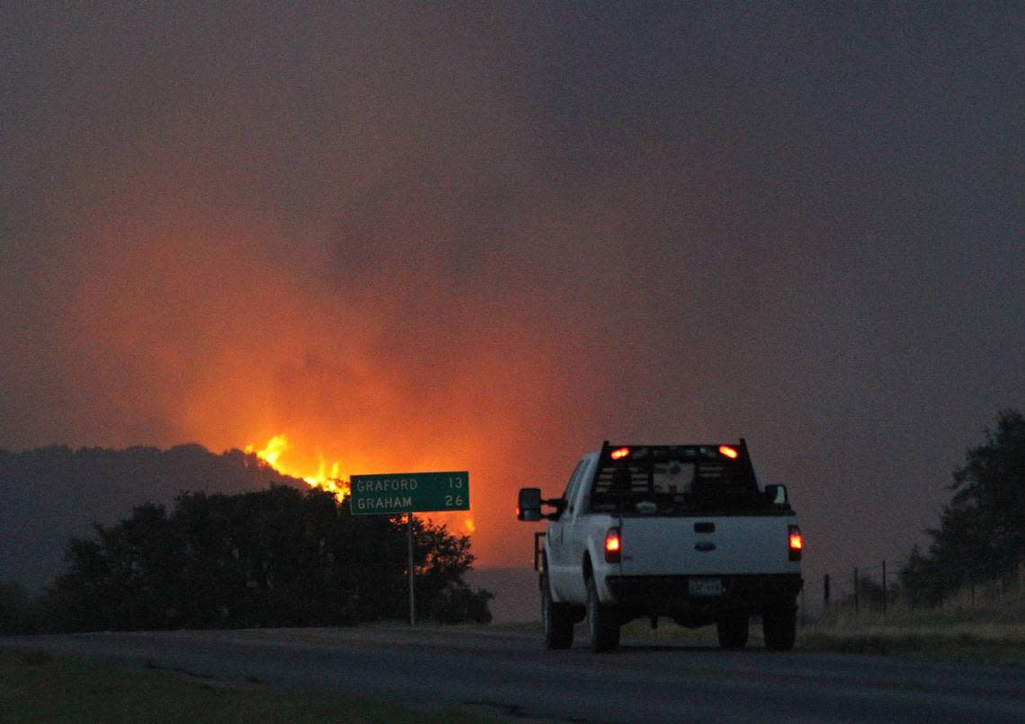 A truck races to the scene as a hillside along Texas 16 erupts in flames near Possum Kingdom Lake on April 15, 2022.