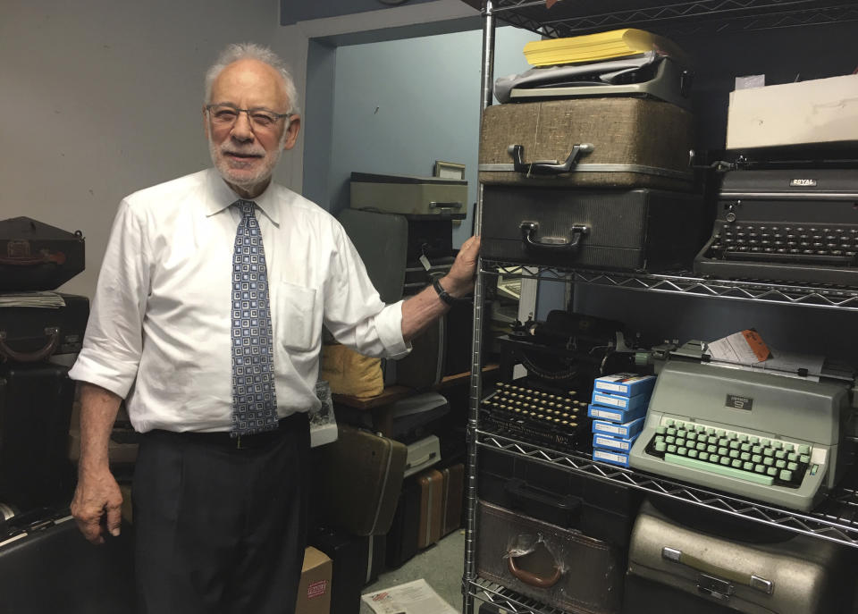 This June 28, 2019 photo shows Paul Schweitzer standing in the Gramercy Typewriter Co. repair shop in New York, alongside a shelf of vintage typewriters. Schweitzer who, with his son, owns the Gramercy Typewriter Co, founded by Schweitzer's father in 1932. Vintage typewriters are sent for repair and restoration daily from around the country, Schweitzer says. (Katherine Roth via AP)