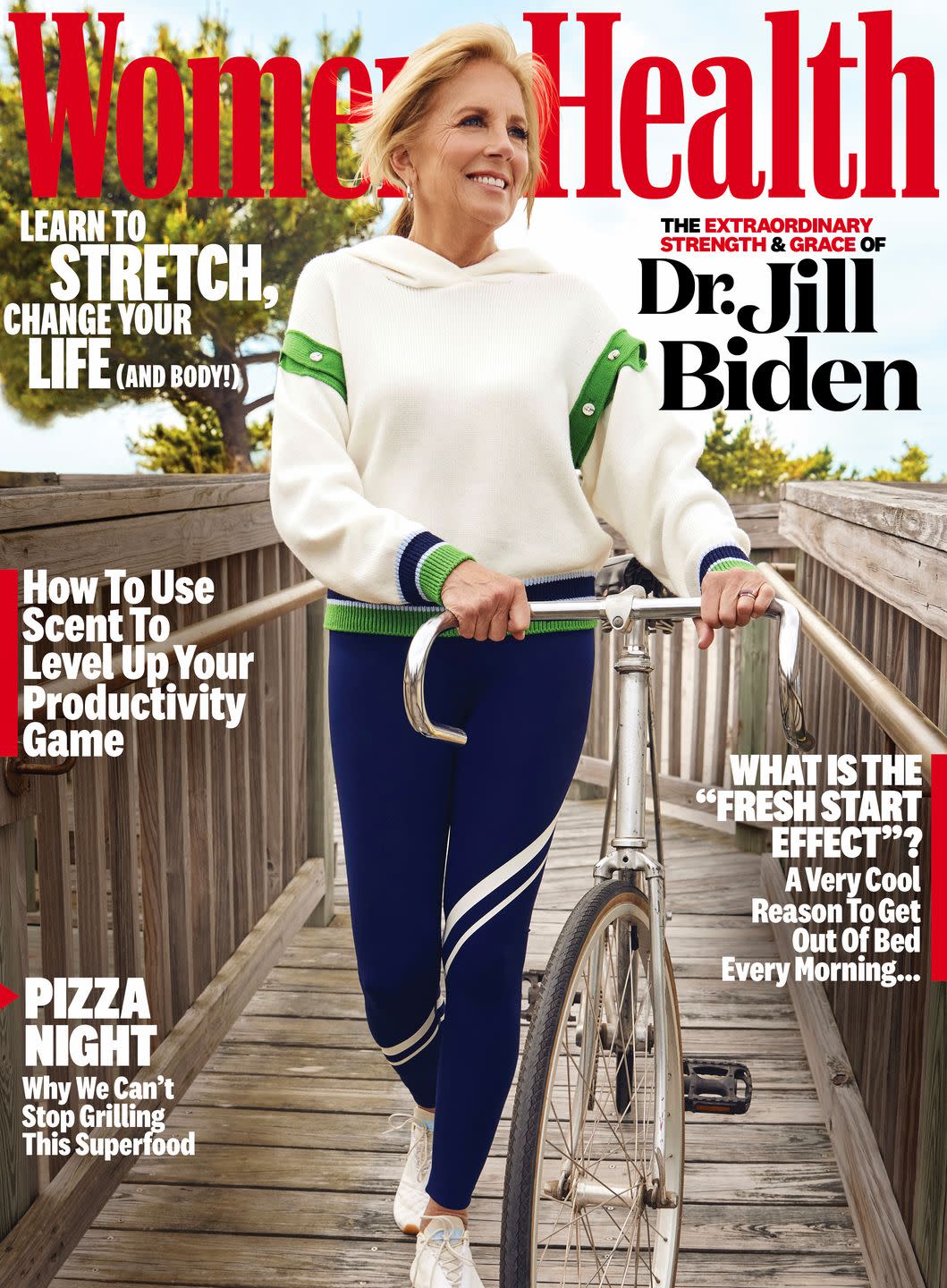women's health cover with first lady jill biden walking along boardwalk, smiling and holding onto a bike, coming from the beach