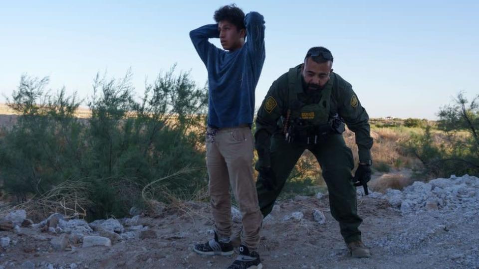 Un guarda fronterizo catea a un migrante en la frontera