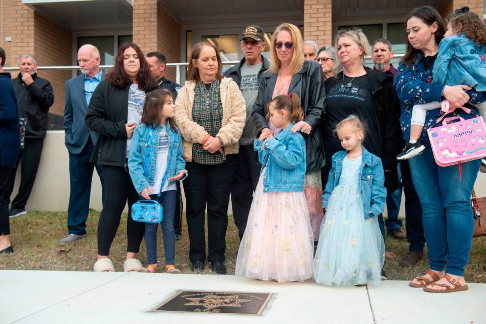 Members of Steven Robin’s family remove a sheet covering a metal star during a ceremony dedicating commemorative stars in honor of Sergeant Steven Robin and Officer Branden Estorffe outside the new Bay St. Louis Police Department in Bay St. Louis on Thursday, Dec. 14, 2023. Estorffe and Robin were killed on Dec. 14, 2022 by a local veterinarian when they responded to a call at a Motel 6.