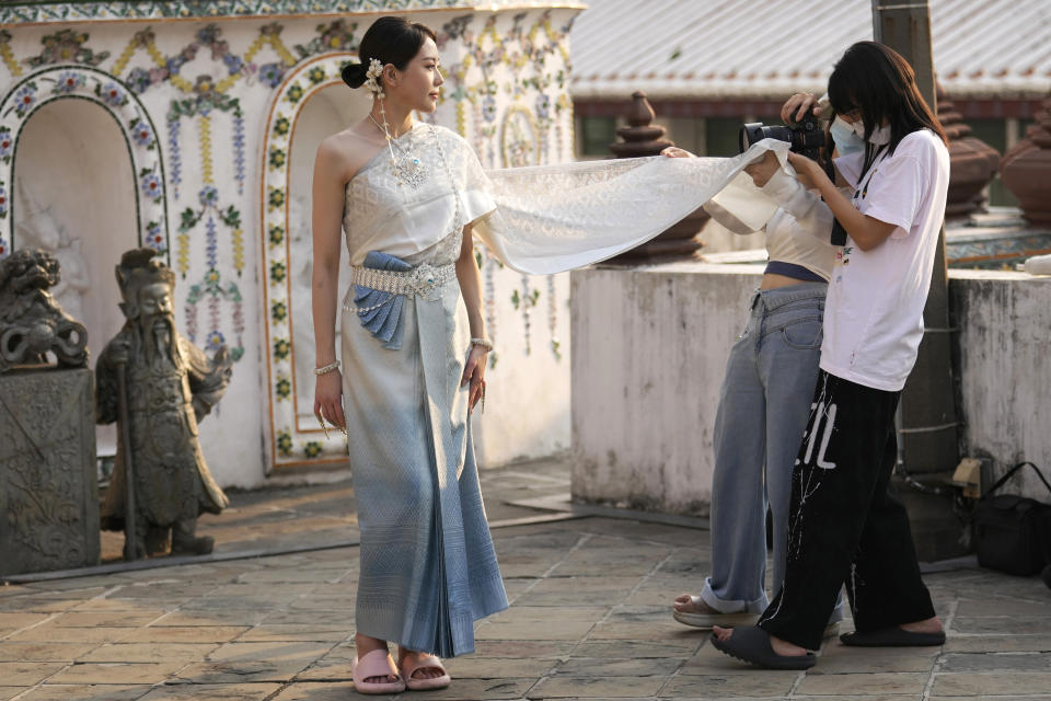 FILE - A Chinese tourist rents traditional Thai costumes and poses for a photographer at Wat Arun, or the "Temple of Dawn," in Bangkok, Thailand, on Jan. 12, 2023. Thailand's new cabinet has approved a temporary visa exemption for tourists from China and Kazakhstan in its first meeting on Wednesday, Sept. 13, for a bid to boost tourism and the economy. (AP Photo/Sakchai Lalit, File)