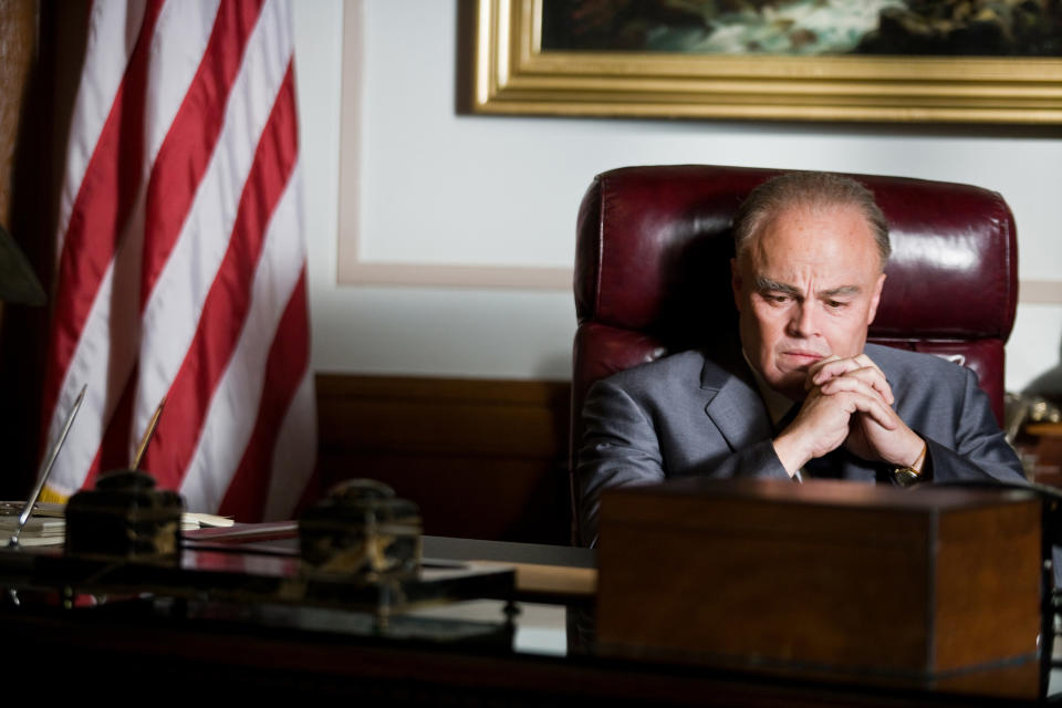 Leonardo DiCaprio wearing old age makeup sits at a desk