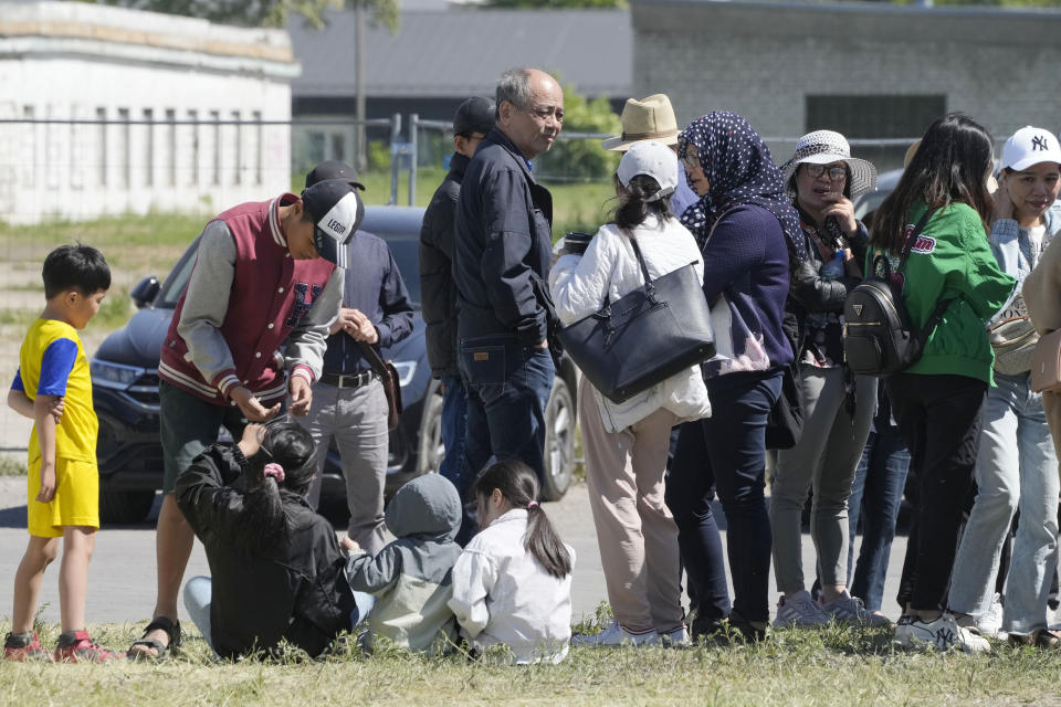 Vietnamese traders and their families gathered before a temporary fence put up to block access to a burnt-down shopping center in Warsaw, Poland, on Wednesday, May 15,2024. A weekend fire at the Marywilska 44 shopping center dealt tragedy to many members of Poland's Vietnamese community. People lost entire livelihoods and say they don't know how they will manage to make a living. (AP Photo/Czarek Sokolowski)