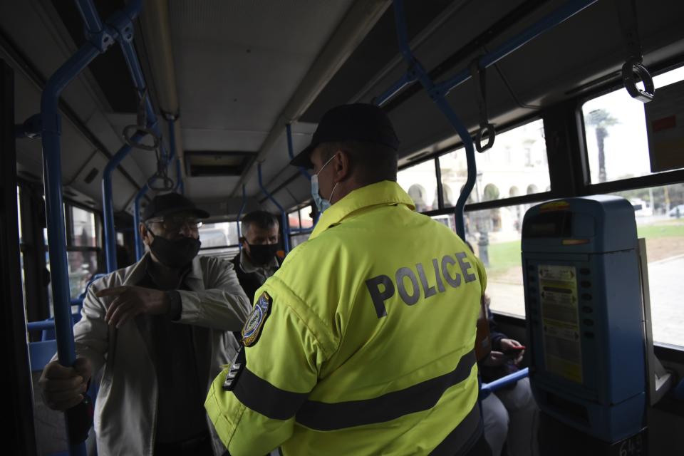 A policeman checks the passengers of a bus during the lockdown to contain the spread of COVID-19 in the northern city of Thessaloniki, Greece, Tuesday, Nov. 3, 2020. Greece's government imposed a localized lockdown on its second largest city of Thessaloniki and the northern province of Serres, after major increases in the number of coronavirus infections there. (AP Photo/Giannis Papanikos)