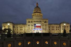 A large Texas flag hangs from the Texas State Capitol as workers prepare the grounds for inauguration ceremonies in Austin on Jan. 14, 2019.