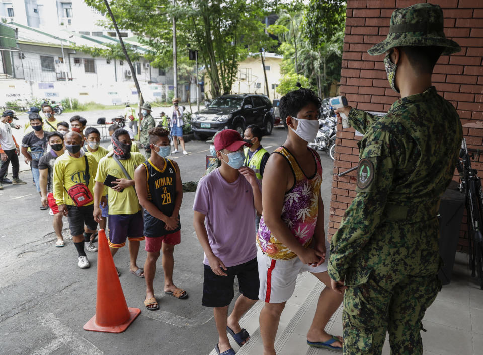 Men who were arrested for violating quarantine health protocols have their temperatures checked at the Amoranto Sports Complex in Manila, Philippines on Wednesday, July 8, 2020. Philippine President Rodrigo Duterte eased one of the world's longest lockdowns in the Philippine capital of more than 13 million people on June 1 after the economy shrank in the first quarter in its first contraction in more than two decades. (AP Photo/Aaron Favila)