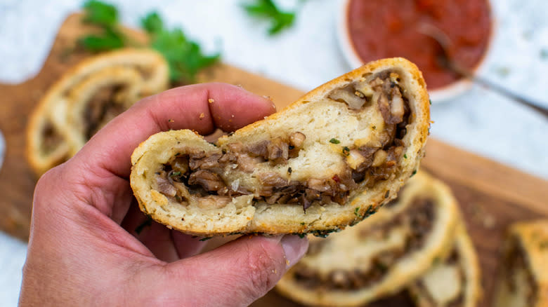 hand holding mushroom Stromboli slice