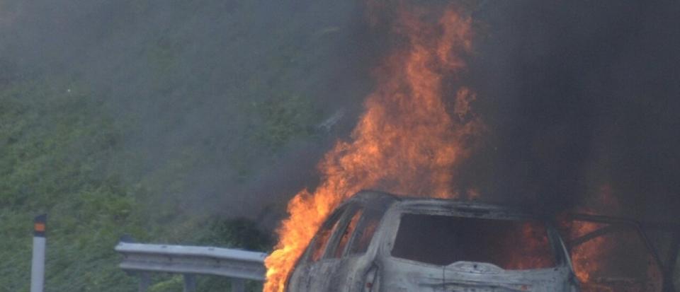 Burnt car at roadside by hill