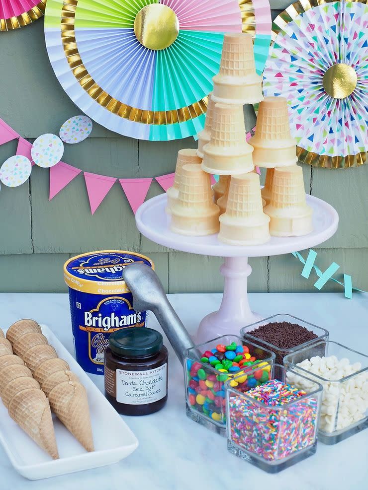 an ice cream bar with cones, toppings, sauces and other treats