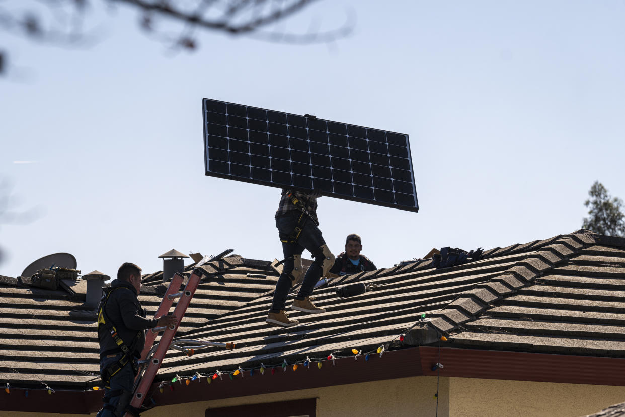 Workers preparing to install solar panels on a roof of a home in Hayward, Calif. 