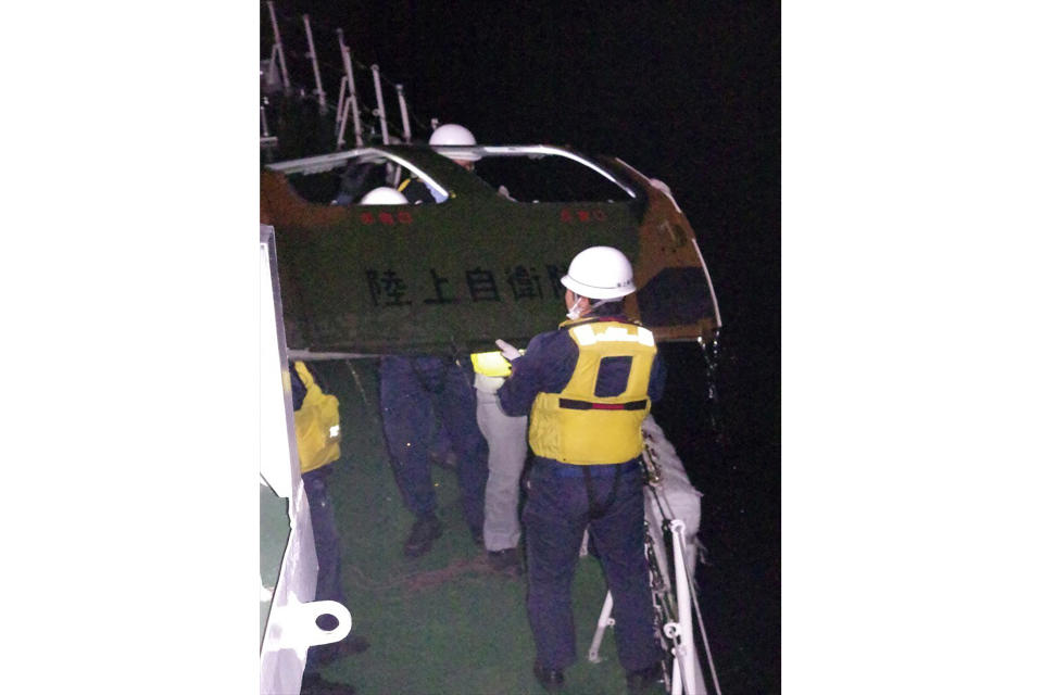 In this photo provided by the 11th Regional Japan Coast Guard Headquarters, coast guard members retrieve a door from the sea, off Miyako Island, Okinawa Prefecture, southern Japan, Friday, April 7, 2023. The words on the door reads Ground Self Defense Force. Search and rescue operation continued Friday and officials said they found a door and other fragments believed to be of a Japanese army helicopter presumed to have crashed into the sea near southern islands with 10 crew members on board. (11th Regional Japan Coast Guard Headquarters via AP)