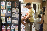 <p>Pictures of children sponsored by Bill Clay, second left, and his wife, Kristi, are displayed on their refrigerator as they prepare breakfast for their children, Ami, left, and Xavier at their home in Ashville, Ohio, on Saturday, July 9, 2016. Kristi Clay opposes same-sex marriage and abortion and names those as her top issues. Yet the 32-year-old school librarian reluctantly leans toward Clinton, because she feels Trump is materialistic and prefers the Democratic views on immigration and poverty. (AP Photo/John Minchillo) </p>