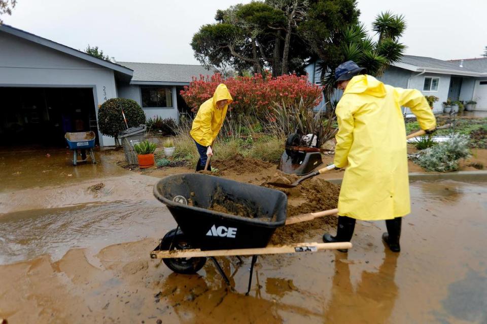 Los Osos resident Bruce Hendry joined the cleanup effort with his son, Sawyer, and rain splashed on the pair as they shoveled mud out of Kay Blaney’s driveway on Vista Court on Tuesday, Jan. 10, 2023. A water retention basin failed and sent a torrent of floodwater pouring down onto the neighborhood from the hillside above.