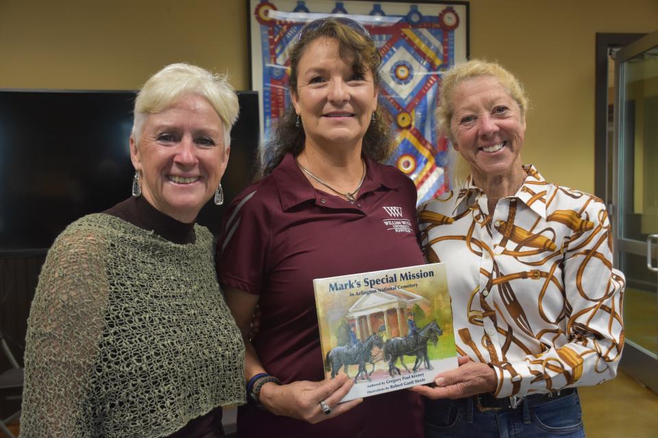 Friends Jill Czarnowski (right), Juliette Ritzman and Jackie Jarboe hold the children's book "Mark's Special Mission in Arlington National Cemetery" at the Jaekcle Centre in Thompson's Station, Tenn. on Monday, Aug. 1, 2022. Ritzman is the new adoptive owner of Mark, the book's subject, and stopped in Tennessee as she drove him to his new home in Missouri where they'll retire together.