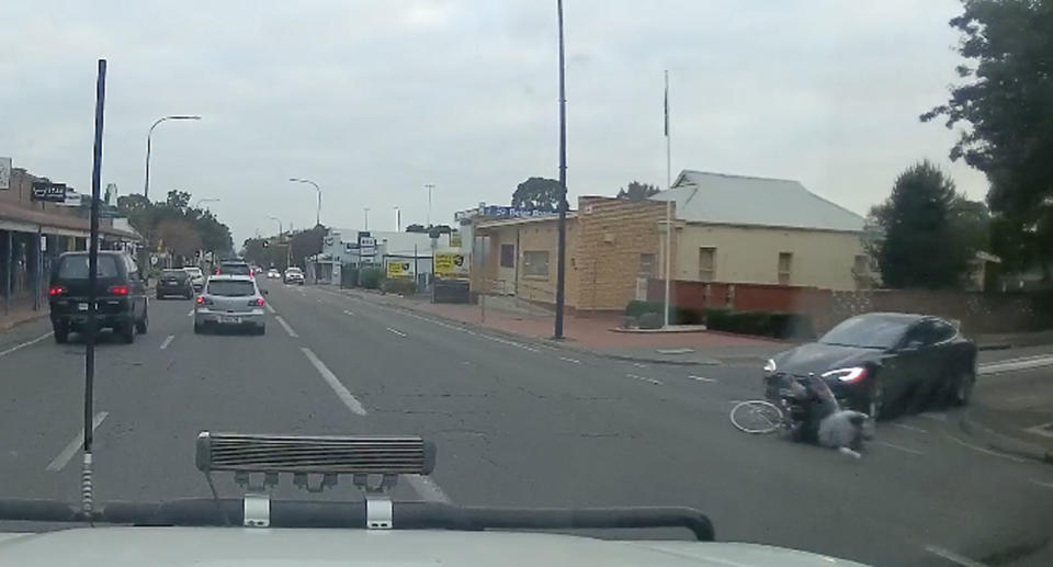 The driver of the Tesla knocks the cyclist off the bike. Source: Facebook/ Dash Cam Owners Australia