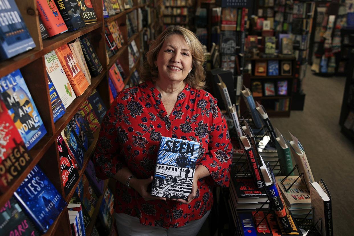 Jacksonville author Julie Delegal is shown with her newly published fiction book, "Seen," at San Marco Books and More. The novel is inspired by the 2000 Brenton Butler case in Jacksonville, in which a 15-year-old boy confessed to the murder of a Georgia tourist, then claimed the confession was coerced due to police brutality. A jury quickly acquitted him at trial, and two men were later convicted of the murder.