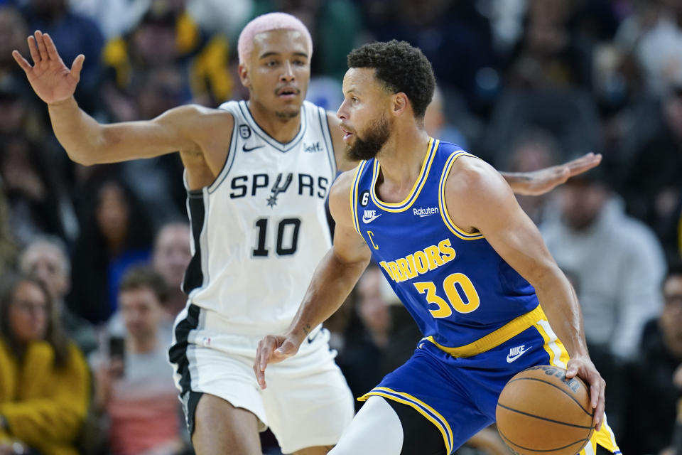 Golden State Warriors guard Stephen Curry (30) moves the ball while defended by San Antonio Spurs forward Jeremy Sochan (10) during the first half of an NBA basketball game in San Francisco, Monday, Nov. 14, 2022. (AP Photo/Godofredo A. Vásquez)