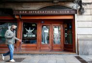 FILE PHOTO: A man wearing protective face mask walks past a closed restaurant in Barcelona